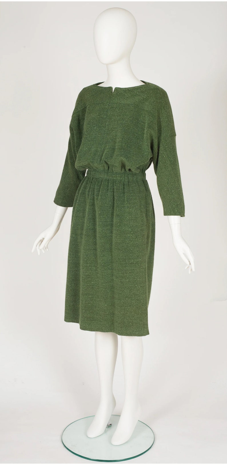 Puede incluir: Un vestido verde de manga larga con cuello redondo y cintura fruncida.