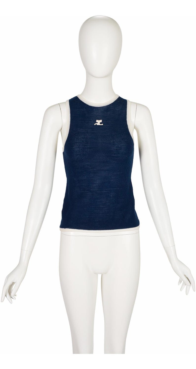 Peut inclure: Un d&eacute;bardeur bleu marine avec une bordure blanche et un petit logo blanc sur la poitrine. Le haut sans manches est pr&eacute;sent&eacute; sur un mannequin. Le haut est en tissu tricot&eacute; doux.