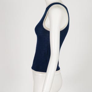 Peut inclure: Un d&eacute;bardeur bleu marine avec une bordure cr&egrave;me. Le haut sans manches est pr&eacute;sent&eacute; sur un mannequin, mettant en valeur sa coupe ajust&eacute;e. La bordure est visible autour de l'encolure et des emmanchures.