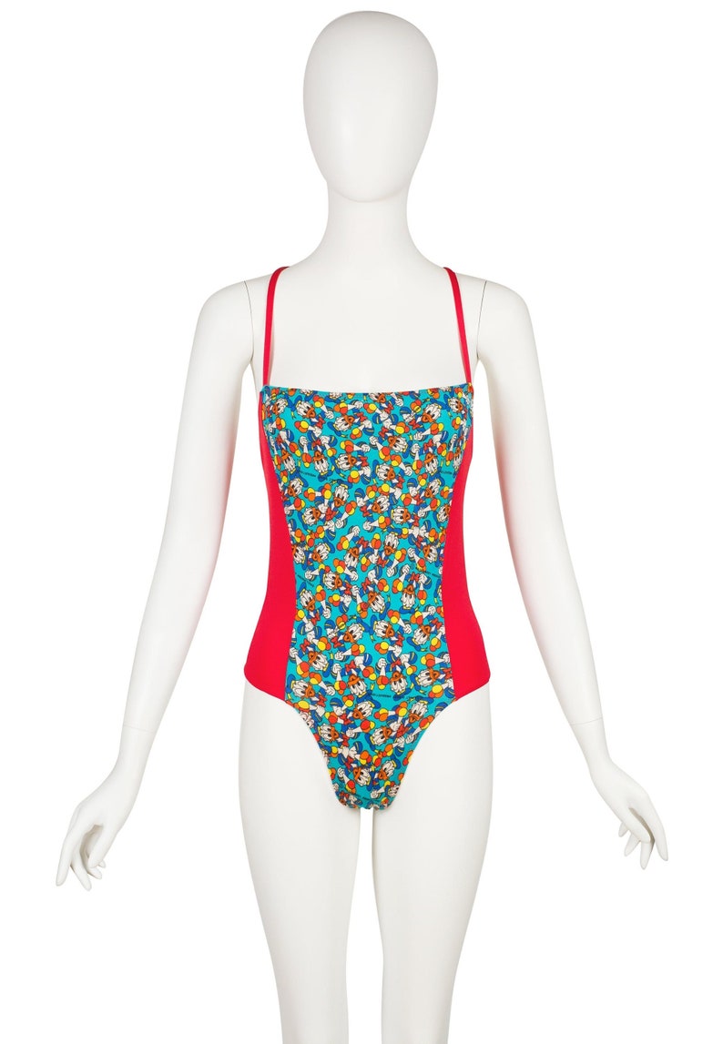 May include: A red and blue one-piece swimsuit with a cartoon print. The swimsuit has thin straps and a scoop neck.