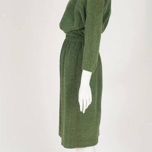 Puede incluir: Un vestido verde de manga larga con cuello redondo y cintura fruncida.