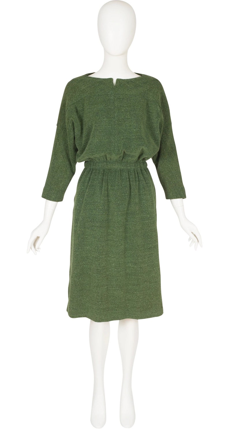 Puede incluir: Un vestido verde de manga larga con cuello redondo y cintura fruncida.