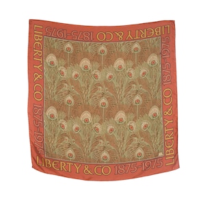 May include: A red silk scarf with a repeating pattern of green peacock feathers. The scarf has a border with the text "LIBERTY & CO 1875-1975" repeated on all four sides.