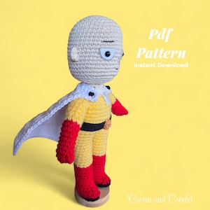 Könnte beinhalten: Gehäkelte Superheldenfigur in gelbem Anzug, weißem Umhang und roten Stiefeln. Die Figur hat einen kahlen Kopf und einen ernsten Gesichtsausdruck. Der Text "Pdf Pattern Instant Download" ist im Bild enthalten.