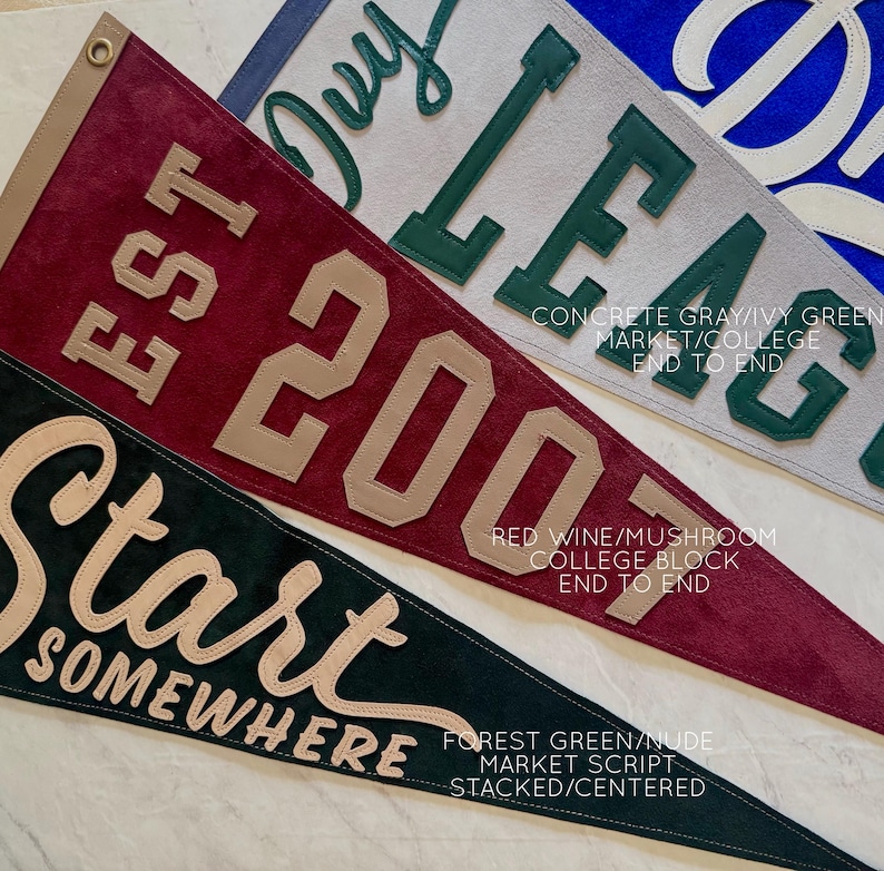 May include: Three felt pennants in shades of red, gray, and green. The pennants feature text in contrasting colors, including "EST 2007", "Ivy League", and "Start Somewhere". Each pennant has a leather-like trim.
