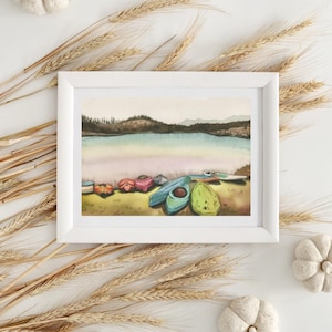 May include: Watercolor painting of a lake scene with colorful kayaks and canoes on the shore. The lake is surrounded by trees and hills in the background. The sky is a soft blue with clouds.
