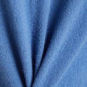 以下が含まれることがあります： 柔らかな青いニット生地のクローズアップ。生地は細かい編み目で、わずかに質感のある表面をしています。