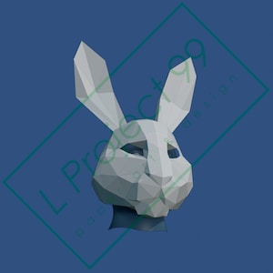 Può includere: Una maschera di coniglio di origami bianca con un design geometrico. La maschera ha orecchie lunghe e un viso dettagliato.