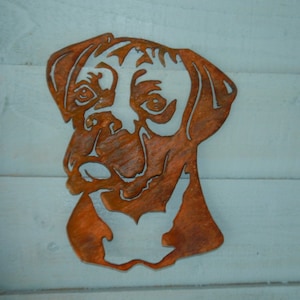 K&ouml;nnte beinhalten: Ein rostiger Metallausschnitt eines Boxerkopfes. Der Ausschnitt ist eine Silhouette des Hundekopfes mit einem detaillierten Gesicht und Ohren.