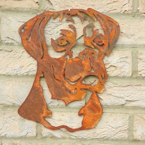 K&ouml;nnte beinhalten: Ein rostiger Metallausschnitt eines Boxerkopfes, der an einer Backsteinwand montiert ist. Der Ausschnitt ist eine Silhouette des Hundekopfes mit Details von Augen, Nase und Maul.