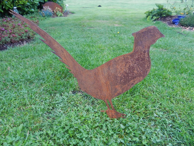 May include: A rusty metal silhouette of a pheasant, standing on a grassy lawn.