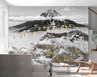 May include: A black and white photograph of a snowy mountain range with a golden glow. The mountain peaks are covered in snow and clouds. There are small golden birds flying in the sky.