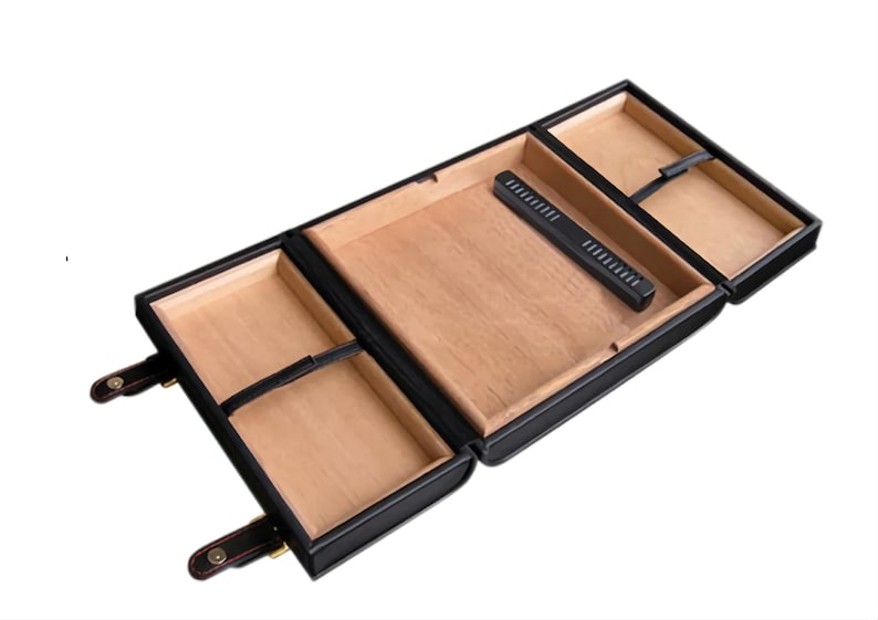 May include: Black leather cigar humidor with a wooden interior. The humidor has multiple compartments and a built-in humidifier. The humidor is open, revealing the interior. The humidor has a rectangular shape and is designed to store cigars.