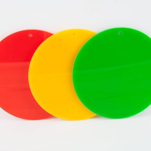 May include: Three round, flat, colourful discs in red, yellow, and green. The discs are arranged horizontally, with the red disc on the left, the yellow disc in the middle, and the green disc on the right.