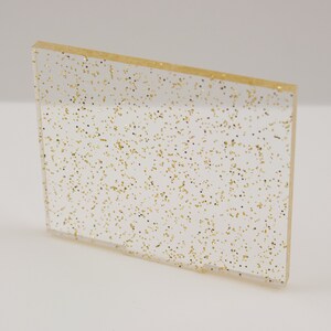 May include: A clear sheet of acrylic with gold glitter embedded throughout.
