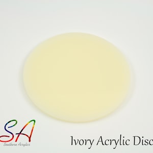 May include: Ivory acrylic disc. The disc is a solid, opaque ivory colour. The text "Ivory Acrylic Disc" is printed in black, along with the "SA" logo in rainbow colours. The disc is a smooth, round shape.