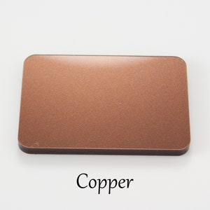 May include: A close-up of a copper-coloured square sample. The sample has a slightly textured surface. The word "Copper" is written below the sample.