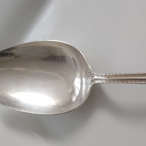 May include: A silver spoon with an ornate handle featuring a floral design. The handle has a blank oval space for engraving.