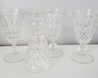May include: Set of four clear glass stemmed drinking glasses with a textured, diamond-like pattern. The glasses are arranged on a white surface.