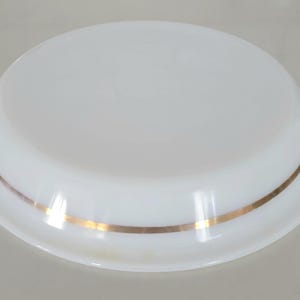 May include: White ceramic plate with a gold rim. The plate is round and has a slightly raised edge.