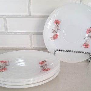 May include: Set of four white vintage floral saucers with pink and brown flowers. The saucers are stacked on top of each other.