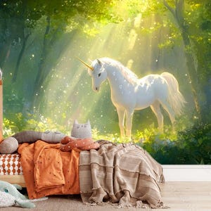 Könnte beinhalten: Ein weißes Einhorn mit goldenem Horn steht in einem sonnendurchfluteten Wald. Das Bild ist ein Wandbild, mit einem hölzernen Bettrahmen und Bettwäsche im Vordergrund. Die Bettwäsche umfasst orangefarbene und beige Decken und Kissen.