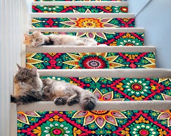 Könnte beinhalten: Zwei Katzen sitzen auf einer Treppe mit bunten, gemusterten Treppenstufen. Die Treppe ist weiß mit einem weißen Geländer. Das Muster auf den Stufen ist eine Mischung aus Rot, Gelb, Grün, Blau und Schwarz.