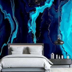 May include: A bedroom with a bed and a nightstand. The wall behind the bed is covered in a blue and gold abstract wallpaper. The wallpaper has a marbled effect with swirls of blue and gold.