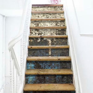 Può includere: Una scala in legno con una carta da parati a motivi che copre i gradini. La carta da parati è un collage di diverse immagini e trame, creando un look unico ed eclettico.