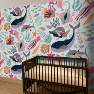 May include: A white nursery wall mural with a colorful underwater scene featuring fish, sea turtles, starfish, and coral. The mural is decorated with a variety of colors, including pink, blue, green, and yellow.