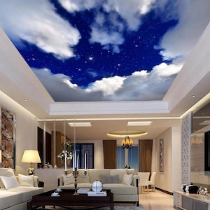 May include: A living room interior with a white ceiling painted to look like a blue night sky with white clouds and stars. The room has a white sofa, a coffee table, and a rug.