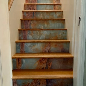 May include: A set of wooden stairs with a marble-patterned vinyl covering. The stairs are in a home and have a natural wood handrail.