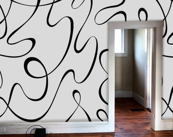 May include: A white wall with a black abstract pattern of curved lines. The wall is in a room with a doorway leading to another room.