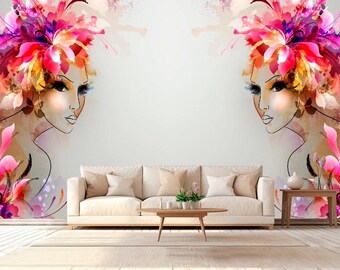 May include: A living room scene featuring a beige sofa, wooden coffee table, and side table. The focal point is a wall mural with two stylized female faces adorned with colorful floral headdresses in pink, orange, and purple hues.