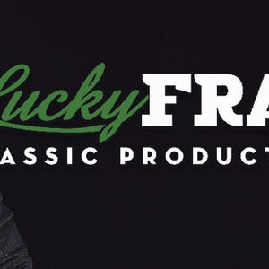 May include: A man in a black suit and tie with a beard and mustache. The text "Lucky FRANC'S CLASSIC PRODUCTS FOR MEN" is in white letters on a black background. The word "Lucky" is in green.