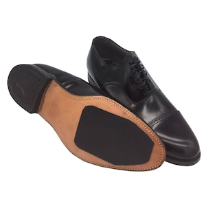 May include: A pair of black leather lace-up shoes with a brown leather sole. The shoes have a classic oxford style.