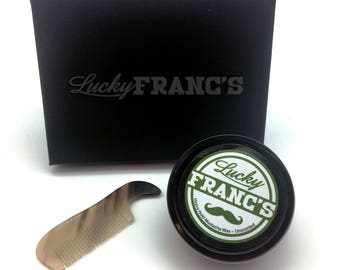 May include: A black box with the text "Lucky Franc's" on the top. A small black jar with a green and white label that says "Lucky Franc's Heavy Hold Mustache Wax - Unscented" and a black and brown comb.