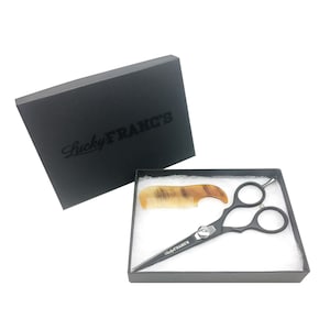 May include: A black box with the text "Lucky Franc's" printed on the top. The box is open and contains a black pair of hairdressing scissors and a brown comb.