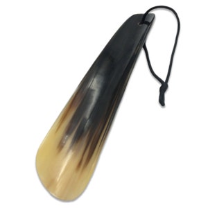 May include: A brown and cream colored shoe horn made of horn with a black cord attached.
