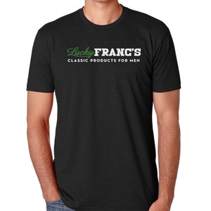 May include: Black t-shirt with white text that reads "Lucky Franc's Classic Products for Men". The text is in a stylized font with the word "Lucky" in green.