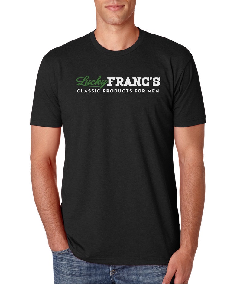 May include: Black t-shirt with white text that reads "Lucky Franc's Classic Products for Men". The text is in a stylized font with the word "Lucky" in green.