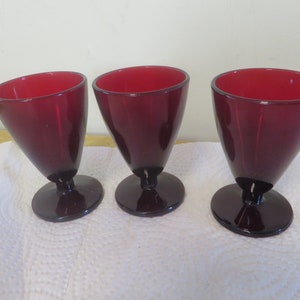 May include: Three ruby red glass goblets with a stemmed base.