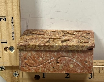 Caja de piedra tallada a mano con diseño floral y tapa decorativa, ideal para guardar objetos coleccionables.