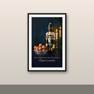 Puede incluir: Una impresión artística enmarcada que muestra un cascanueces junto a un cuenco plateado lleno de nueces y dos velas encendidas. El texto en la parte inferior dice PROFESSIONAL NUT HANDLER References available. El fondo es azul oscuro.