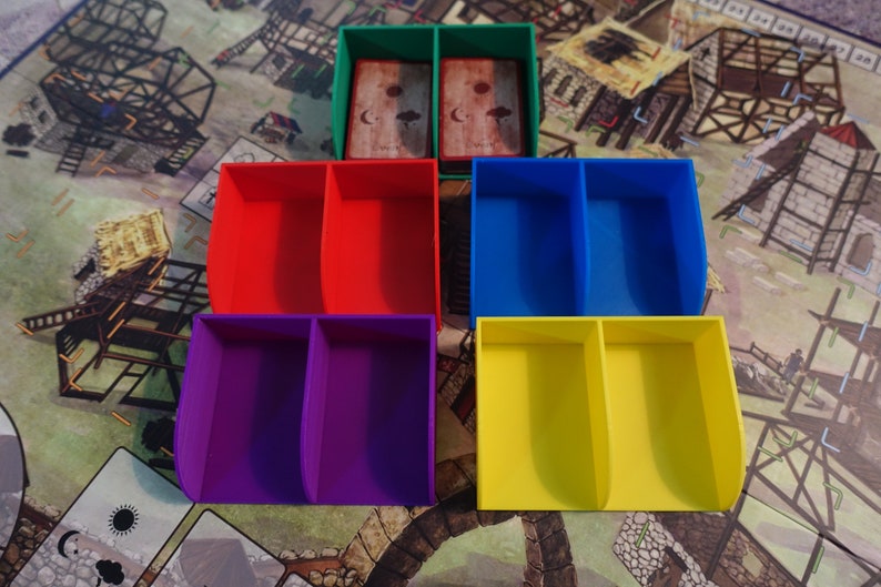 Pu&ograve; includere: Cinque scatole di stoccaggio in plastica con divisori. Le scatole sono verdi, rosse, blu, viola e gialle. Le scatole sono progettate per contenere pezzi di gioco o carte.