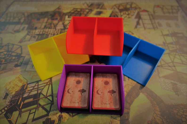 Pu&ograve; includere: Quattro porta carte in plastica colorati, ognuno con due scomparti. I porta carte sono impilati uno sopra l'altro. Il porta carte superiore &egrave; viola e contiene due carte con la parola "Event" stampata su di esse. Gli altri porta carte sono giallo, rosso e blu.