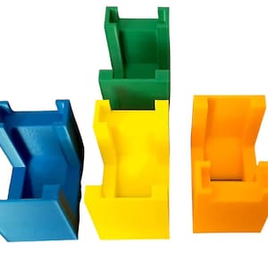 May include: Four plastic building blocks in different colors: blue, yellow, green, and orange. Each block has a unique shape with a hollow center.