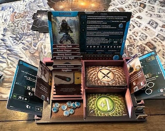 Pode incluir: Um organizador de jogos de madeira com compartimentos para cartas e fichas. O organizador contém cartas com os rótulos "Blinkblade", "Traveling Clock", "Poison Dagger" e "Heavy Sword". Há também um compartimento com um símbolo verde de mais um.