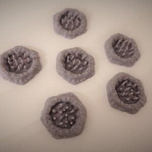 May include: Six gray, hexagonal-shaped, 3D printed terrain pieces with a raised, textured, circular center featuring a cluster of small, pointed spikes.