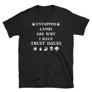 May include: Black t-shirt with white text that reads "Untapped Lands Are Why I Have Trust Issues". The text is surrounded by a circle with a swirl design. Below the text are five symbols representing the five Magic: The Gathering mana colors.